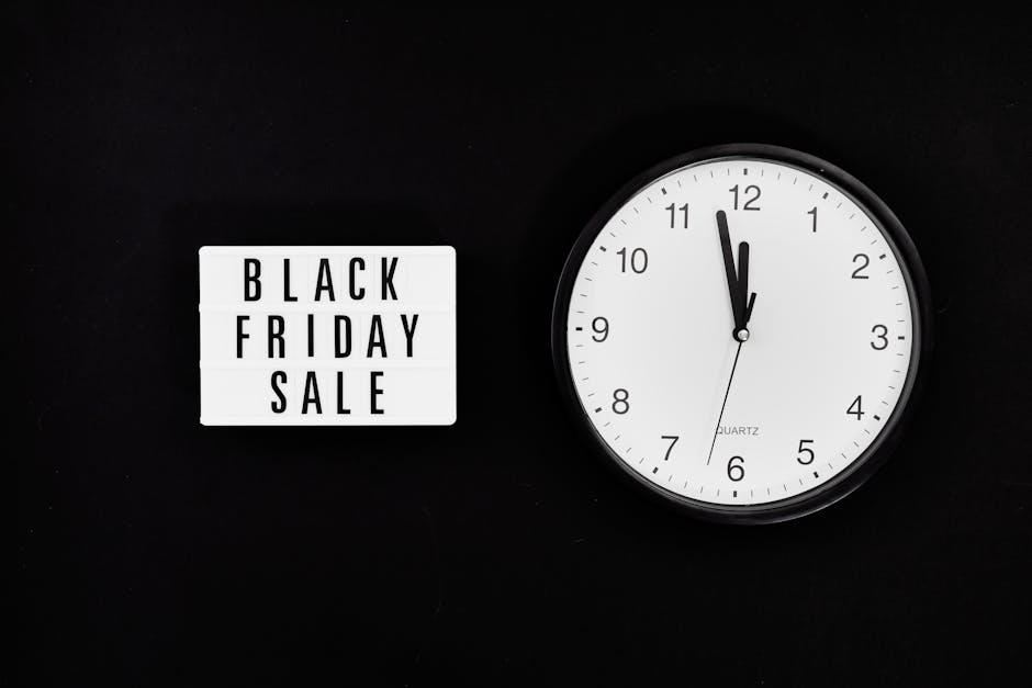 A black background features a small, illuminated white sign with black lettering reading 'Black Friday Sale' positioned on the left side. To the right, there is a round, white wall clock with black nu